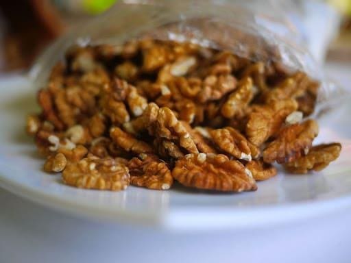 A close-up view of a bag of pecans scattered across a platter.